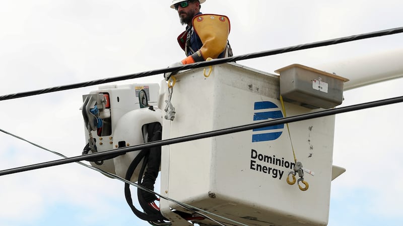 FILE - A Dominion Energy lineman lifts himself up to work on a power line in the aftermath of...