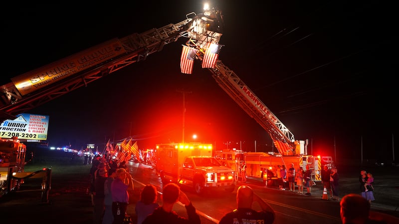People salute as an ambulance drives past during a procession Wednesday, Sept. 17, 2025, in...